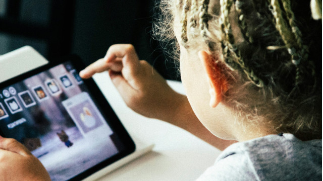 A child alone with a glowing tablet in a dark room